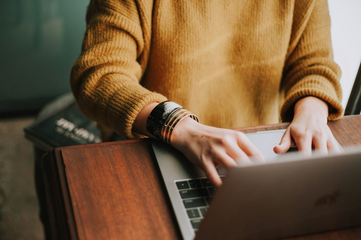 Pessoa digitando em um laptop, em postura de trabalho. Foto: Christin Hume/Unsplash