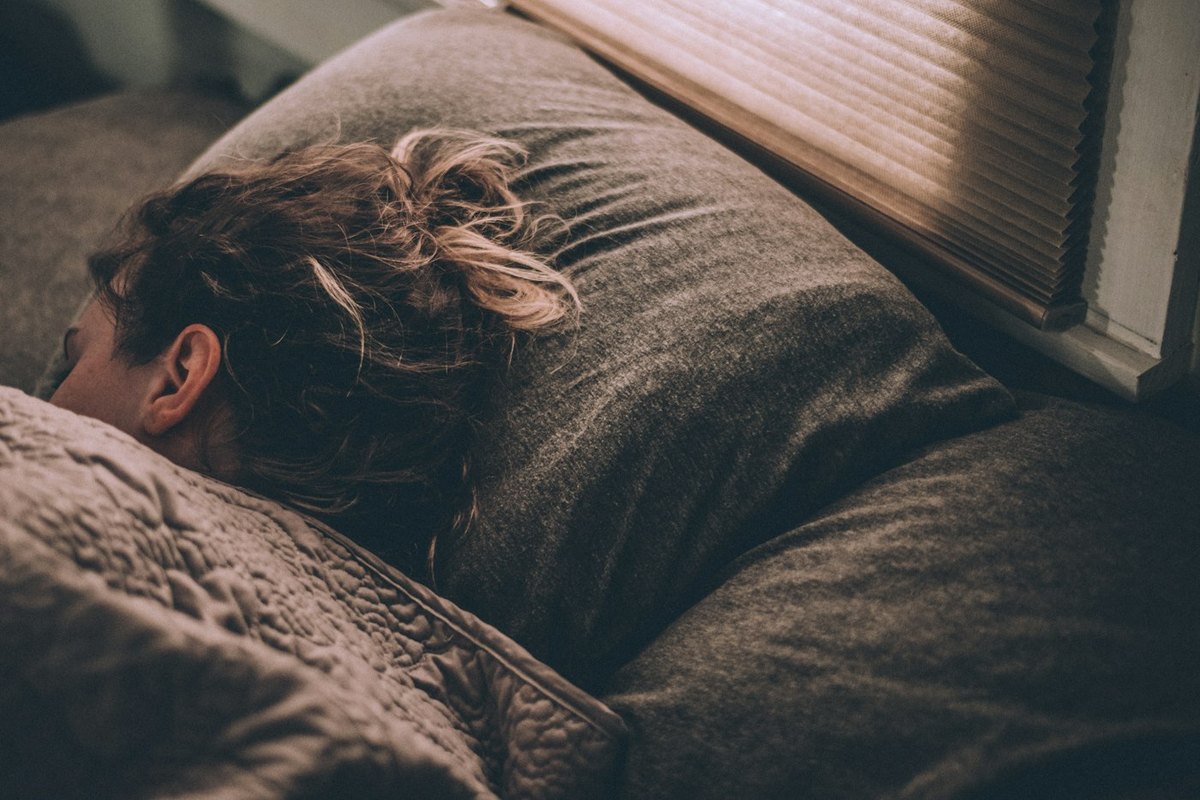 Mulher dormindo em uma cama. Foto: Greg Pappas/Unsplash